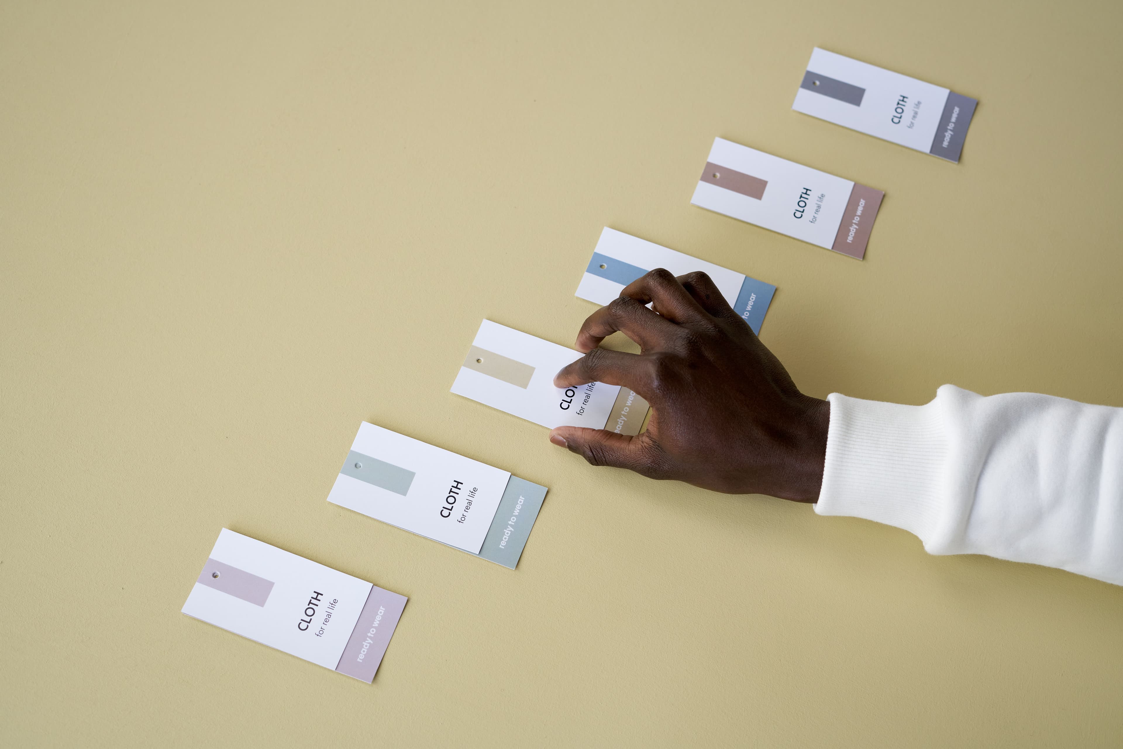 Apparel professional reviewing coordinated neutral and blue color swatch cards for a wholesale assortment refresh